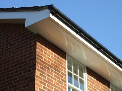 White soffit and fascia with black guttering on a brick house