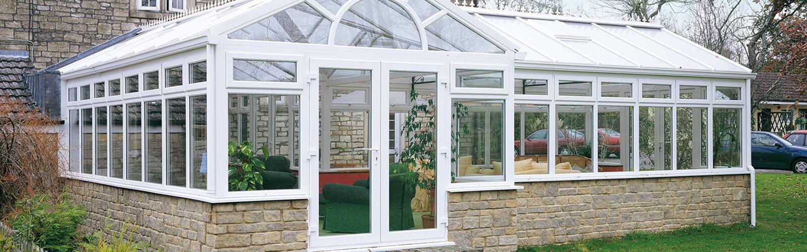 Large white uPVC conservatory with French doors on a stone base