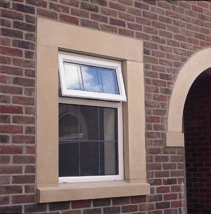 White uPVC tilt window set in a brick wall with stone surround